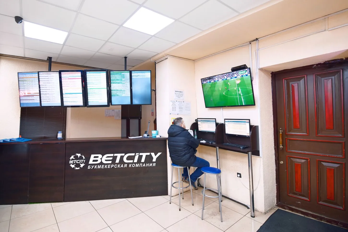 Person sitzt im Wettbüro und schaut sich ein Fußballspiel an