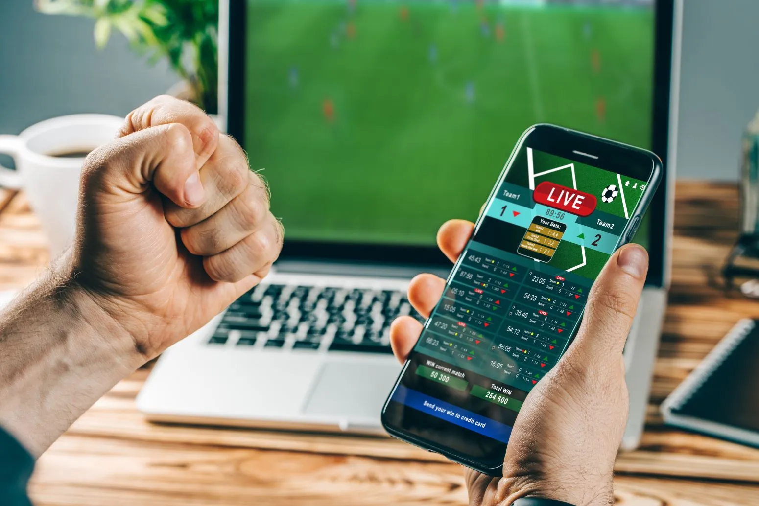 Faust wird neben einem Smartphone mit Fußball Livewetten geballt