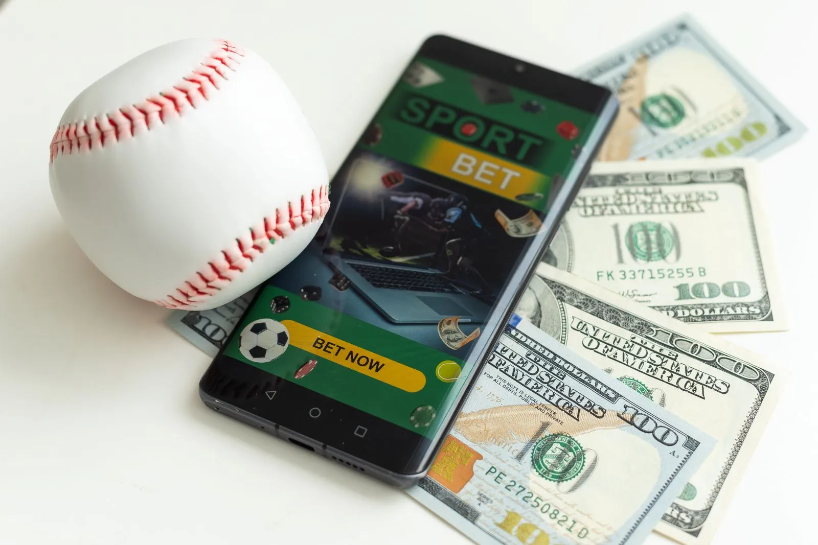 Baseball und Geld liegen neben einem Smartphone mit einer geöffneten Sportwetten App