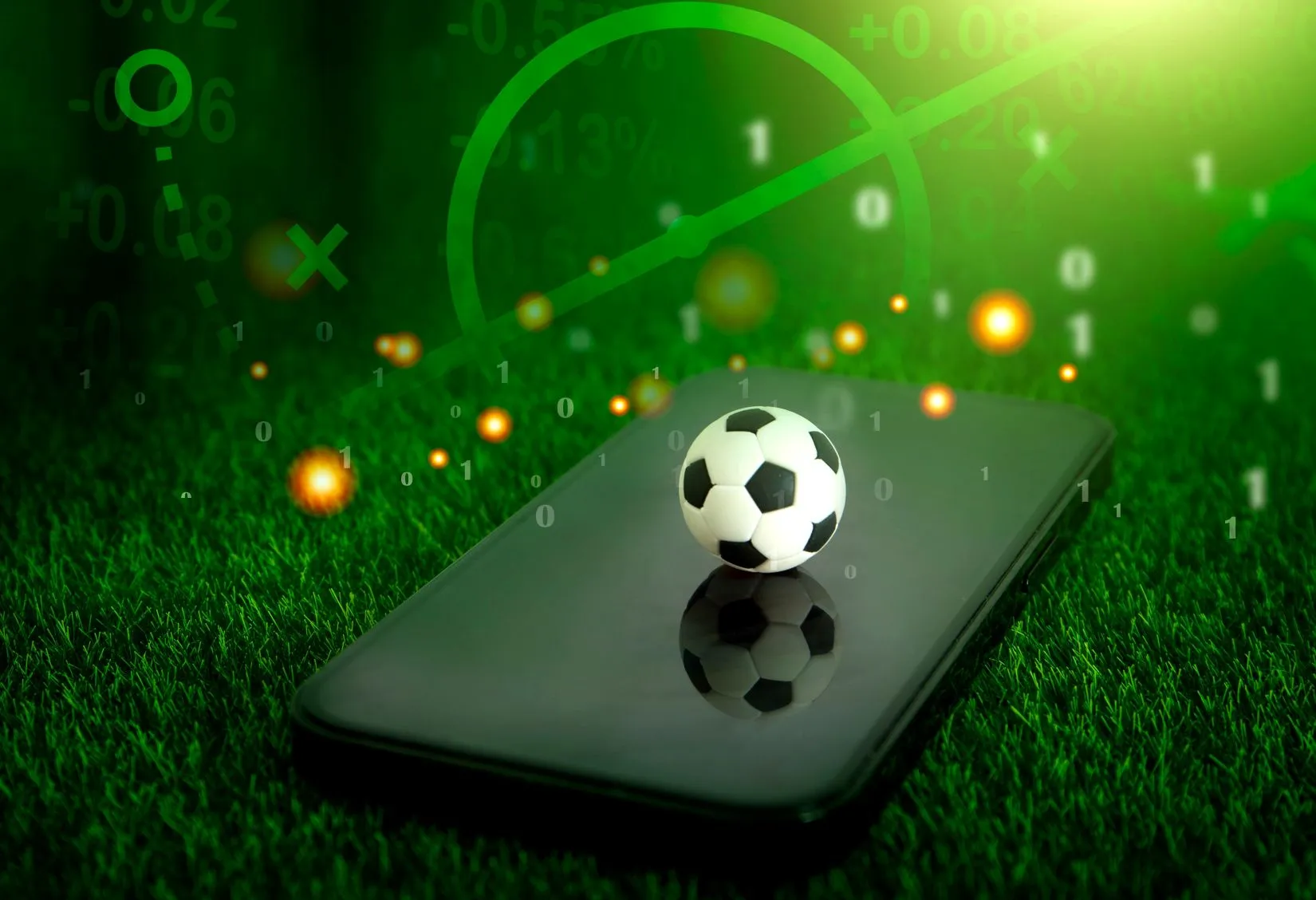 Fußball auf einem Smartphone und im Hintergrund ein Fußballfeld